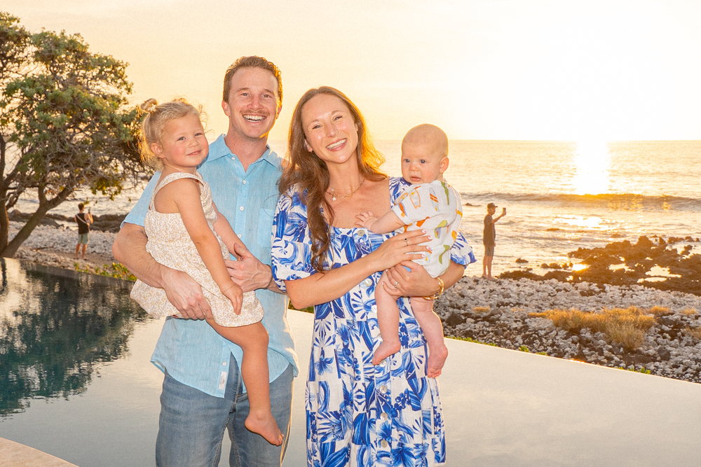 Adam Boehrer with his wife and their two young children on the coast at sunset