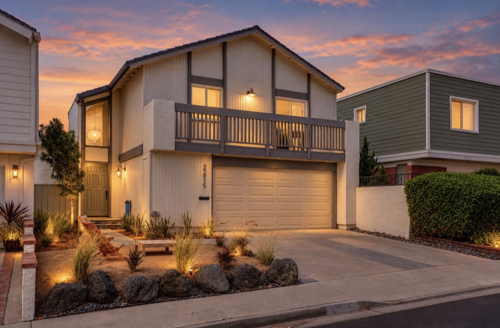 Front of a small remodeled single-story house in San Juan Capistrano at twilight, lights on inside